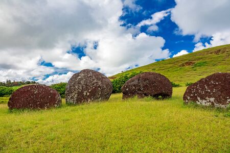 Moai pukaos on the ground under cloudy skyの写真素材