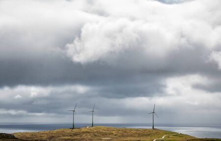 Windmills and road near the ocean under the cloudsの写真素材