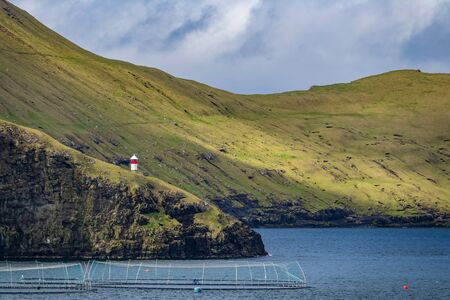 Lighthouse and fishing farms in the fjordの写真素材