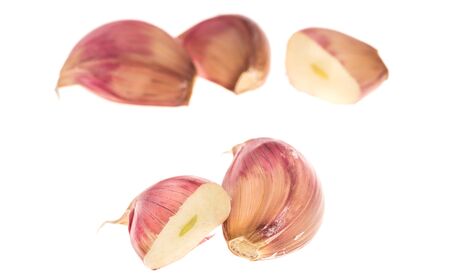 Side view of cloves of garlic and section over white, focus on frontの写真素材