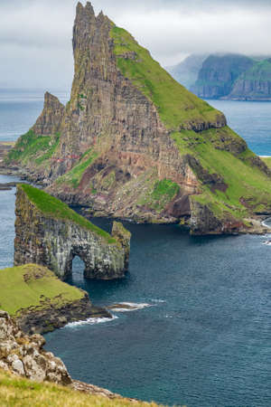 Top amazing view of Drangarnir gate, Tindholmur and Mykines island in the backgroundの写真素材