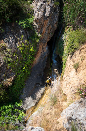 Unrecognizable person canyoning with ropes under the streamの写真素材