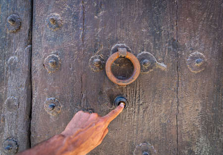 Ringing the vintage wooden door with doorknocker