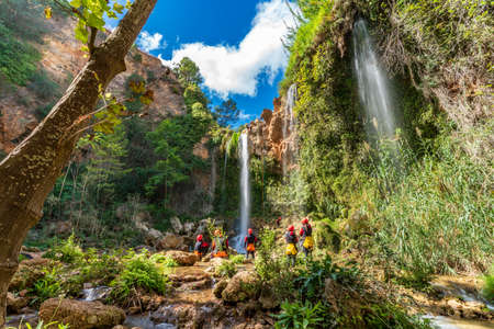 Large group of people enjoy waterfall descent using ropesの写真素材