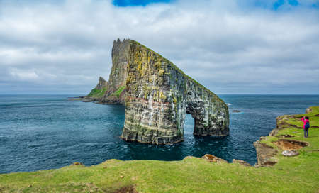 Amazing Drangarnir gate with tourist Faroe Islandsの写真素材