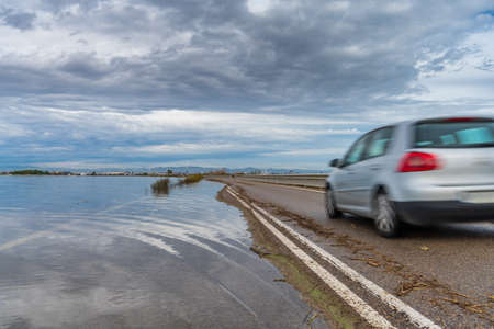 Flooded road and blurred car after the storm with cloudy skyの写真素材