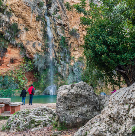 Rear view of unrecognizable tourists looking at the waterfallの写真素材