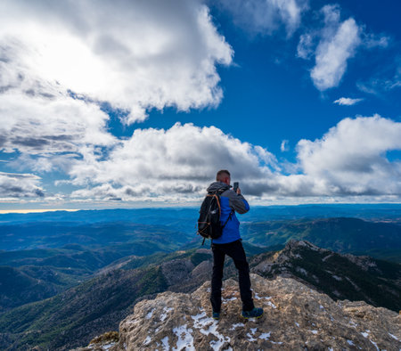 Unrecognizable man taking photos on top of the mountainの写真素材