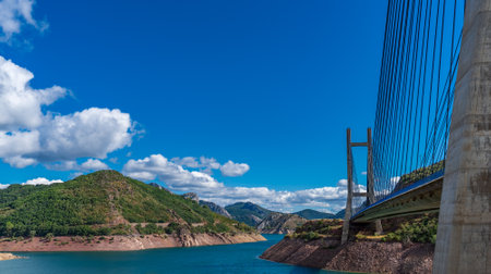 Suspension bridge and dam over blue skyの写真素材