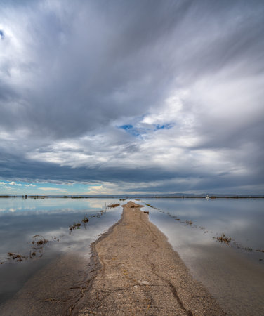 Flooded straight road under cloudy sky after the stormの写真素材
