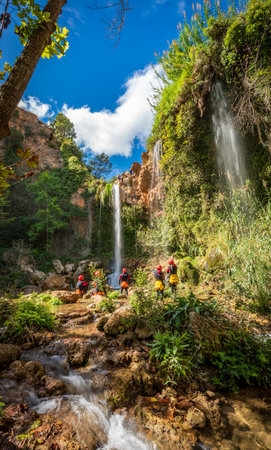 Unrecognizable people enjoy waterfall descent using ropesの写真素材