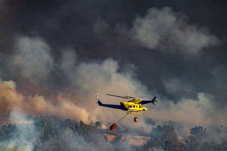 Two helicopters with bambi bucket team working on fire extinctionの写真素材