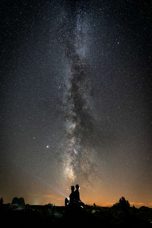 Milky way and two people silhouette with beam lightの写真素材