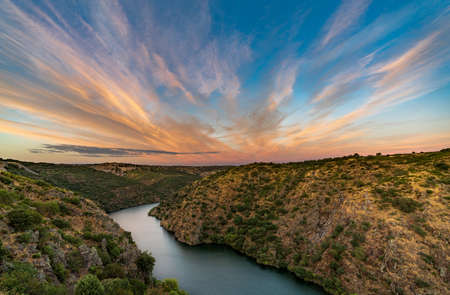River and canyon at sunset with pink cloudsの写真素材