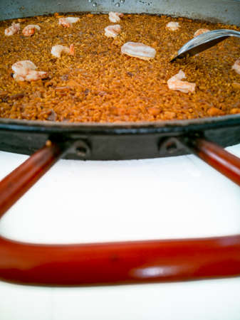 Spanish paella rice closeup view with red handleの写真素材