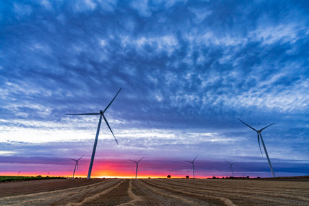 Modern windmills over cultivated fields at awe duskの写真素材