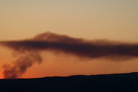 Windmills over the mountain with fire smokeの写真素材