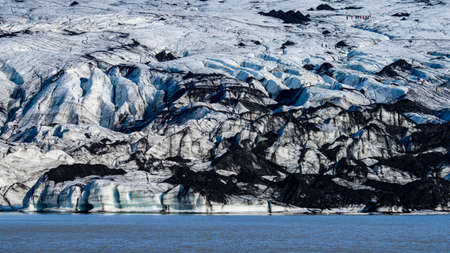 Spectacular glacier tonge with tiny tourists hikingの写真素材