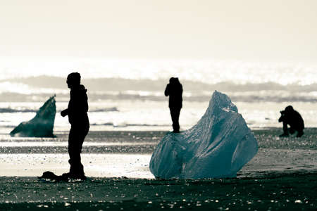 Dark tourists silhouettes enjoy diamond beach