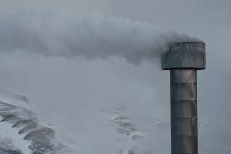 Smokestack with Smoke column and snow covered mountainsの写真素材