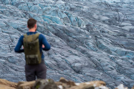 Rear view of unrecognizable tourist against glacierの写真素材
