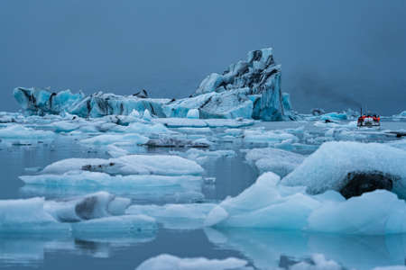Icebergs in Jokulsarlon and group of tourists over boat