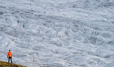 Unrecognizable tourist rear view looking to a massive glacierの写真素材