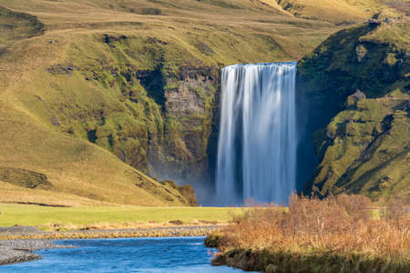 Long exposure of famous Skogafoss waterfall from the distance with hikers on top viewpointの写真素材