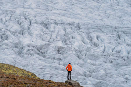 Unrecognizable tourist looking to a massive glacier