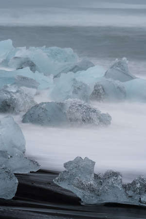 Icebergs over dark Jokulsarlon beach, vertical composition