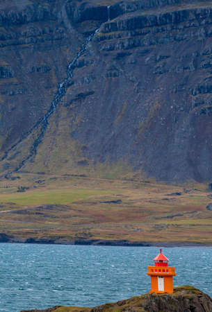 Orange lighthouse near the fjord shore in Icelandの写真素材
