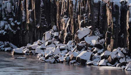 Cube rocks at river shore covered by snow, closeup