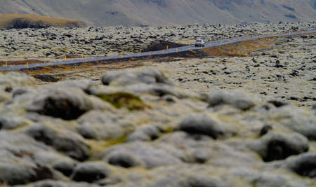 Car driving through lava fields covered by mossの写真素材