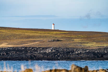 Hidden lighthouse over the volcanic landscape and cloudy skyの写真素材