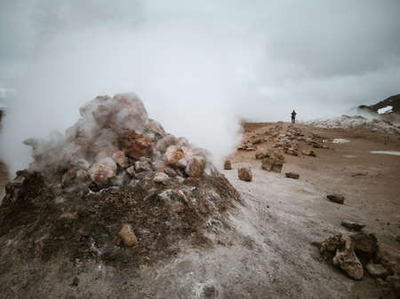 Fumarole heap and tourist walking in the distanceの写真素材