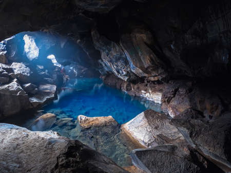 Deep blue lake inside the cave with photographer