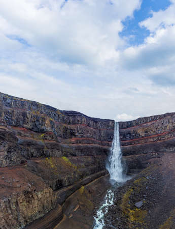Hengifoss waterfall with red layers under cloudy skyの写真素材