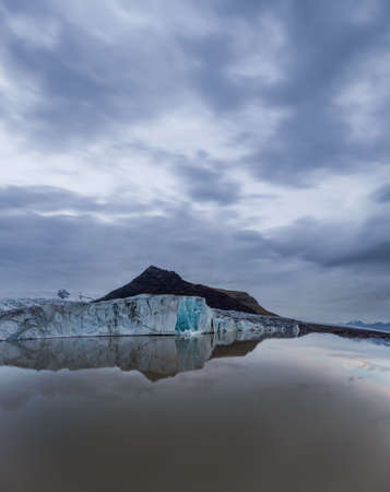 Harsh glacier tongue end over the lake, cloudy skyの写真素材