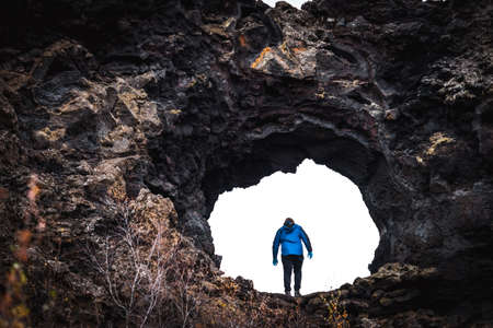 Unrecognizable tourist going through lava field holeの写真素材
