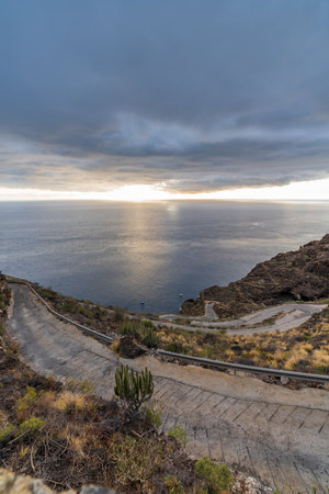 Spectacular steep mountain road top view at sunsetの写真素材