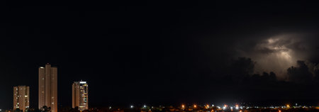 Impressive Skyscrapers Illuminated Against a Dark Stormy Nightの写真素材