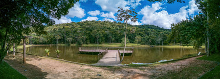 Serene panorama of Juiz de Fora botanical garden lake with wooden platformの写真素材