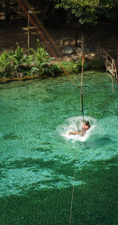 Unrecognizable Woman Splashing into Crystal Clear Lake from a Zip Lineの写真素材