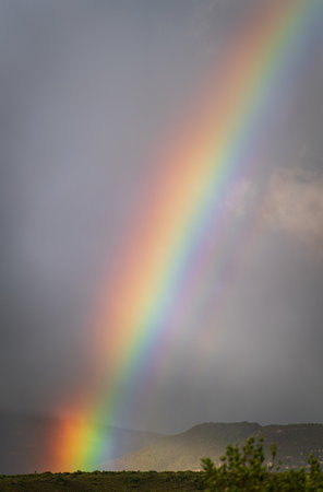 Vibrant Rainbow Emerging above the Stormy Horizon with Rain Loomingの写真素材