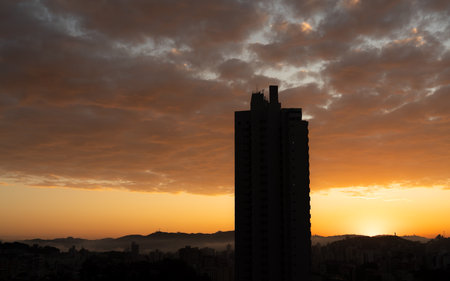 Majestic Skyscraper at Dawn Silhouetted against a Foggy City Skylineの写真素材