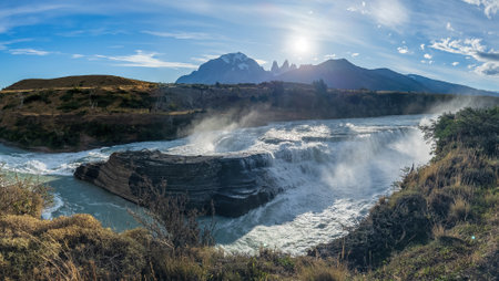 Majestic Waterfall with Mountain Backdrop at Sunriseの写真素材
