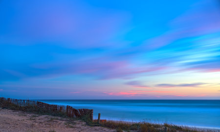 Abstract Beach Sunset with Pink and Blue Clouds, Silky Water and Cottony Skyの写真素材