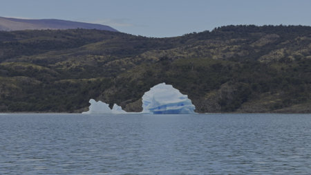 Enormous Iceberg Adrift Close to Shore in Lush Lake Landscapeの写真素材