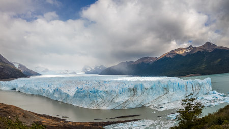 Majestic Glacier View Amidst Mountains and Cloudy Skyの写真素材