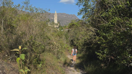 Hiker Walking on Trail Towards a Towering Church Steepleの写真素材